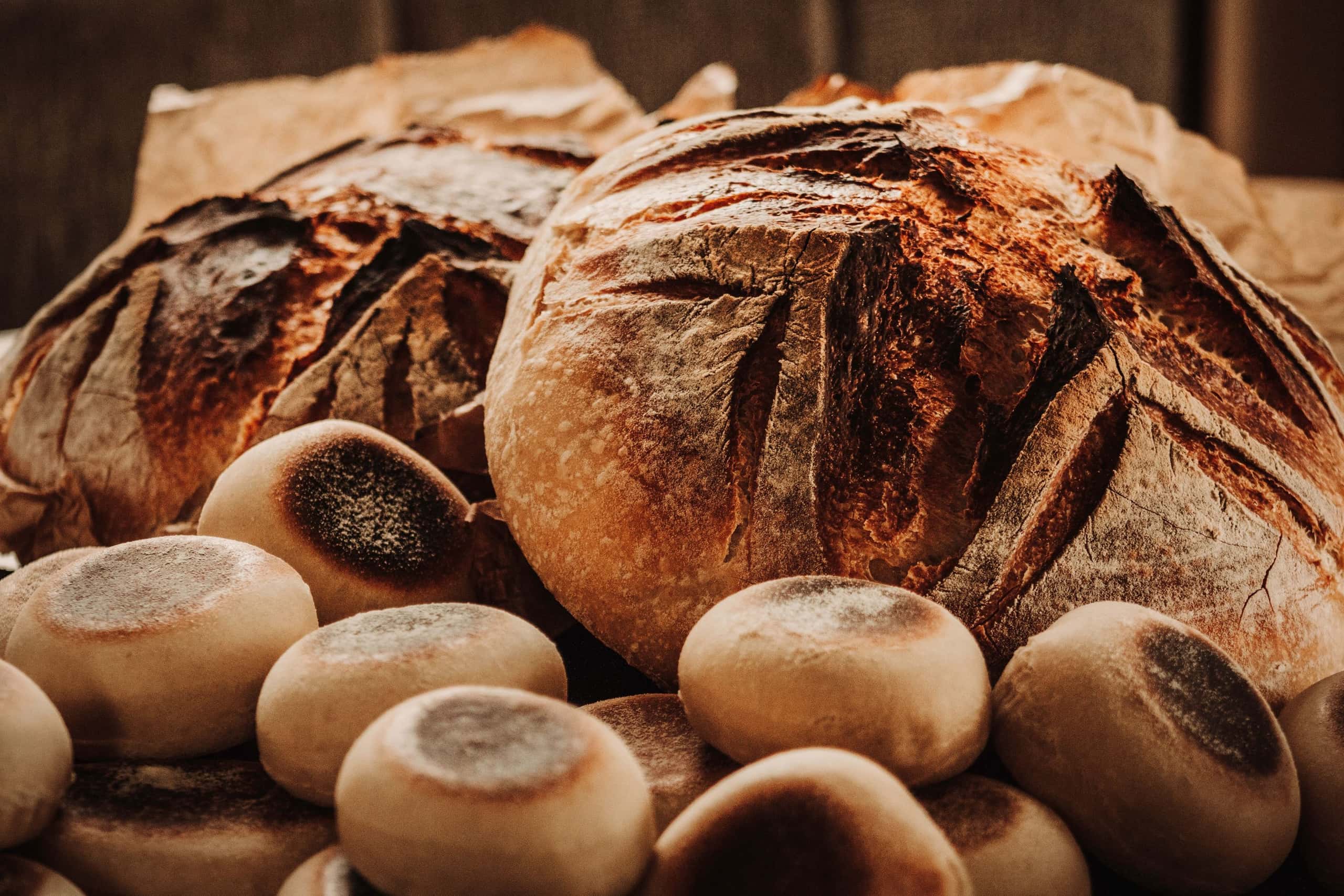 Desembroodjes en een groot rond brood met een gebakken korst op een houten tafel