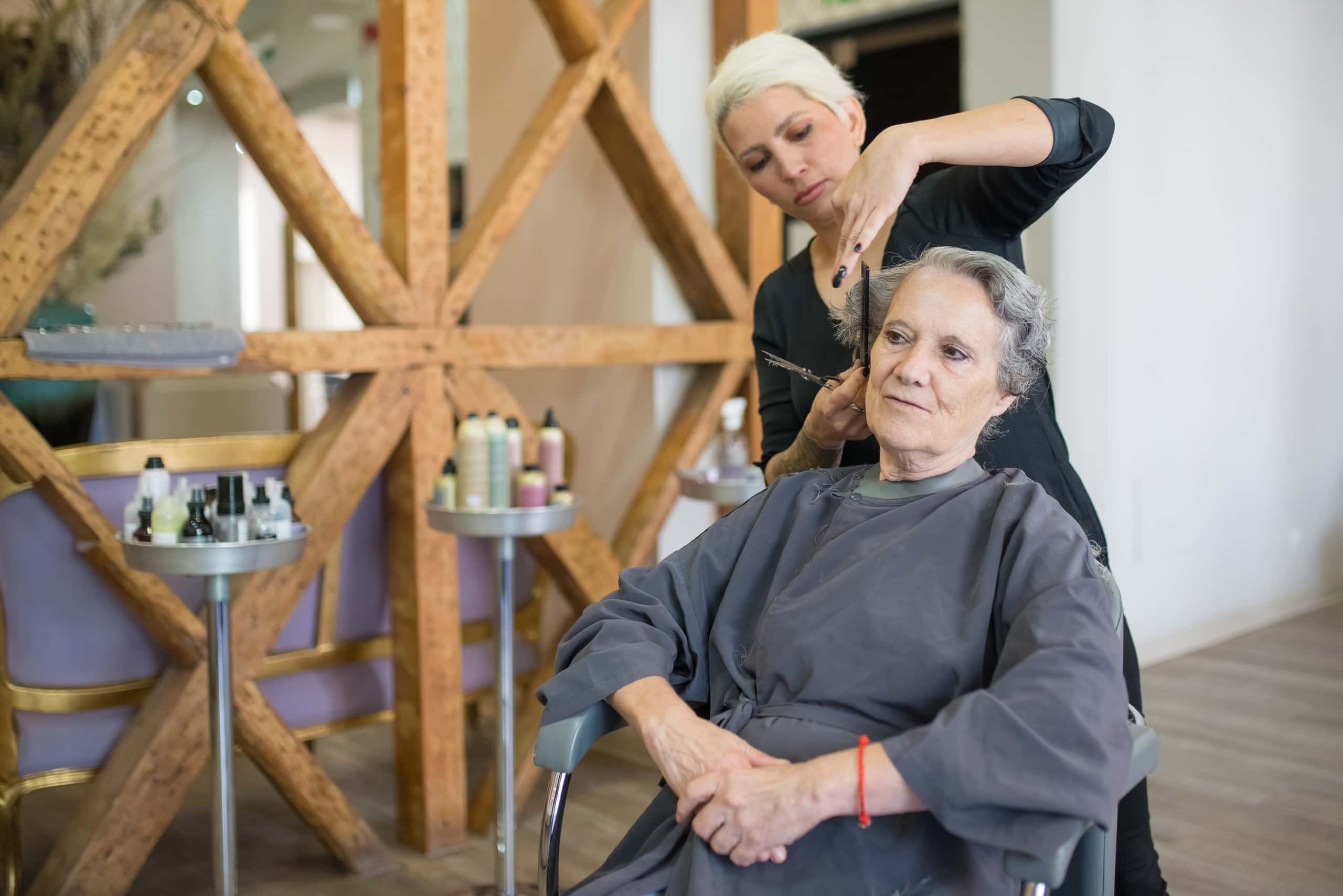 Stylist knipt het haar van een klant naast een houten kruis in de salon