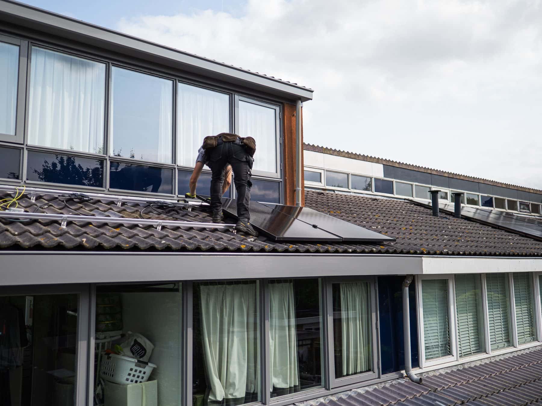 Vakman aan het werk op het pannendak van een woning